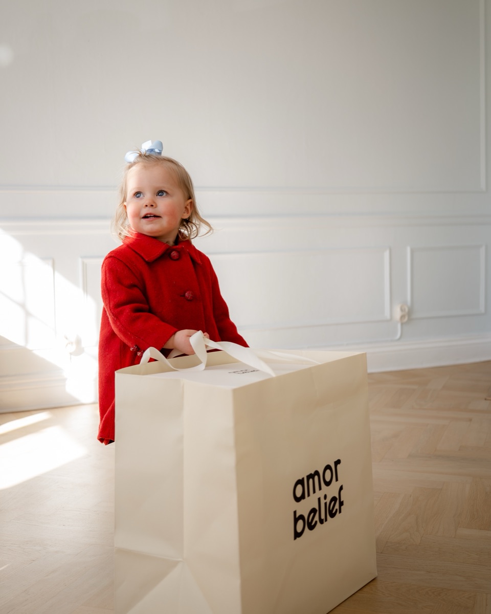 A toddler holding an Amor & Belief shopping bag